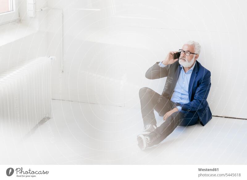 Mature man sitting on the floor using cell phone Businessman Business man Businessmen Business men on the phone call telephoning On The Telephone calling Seated