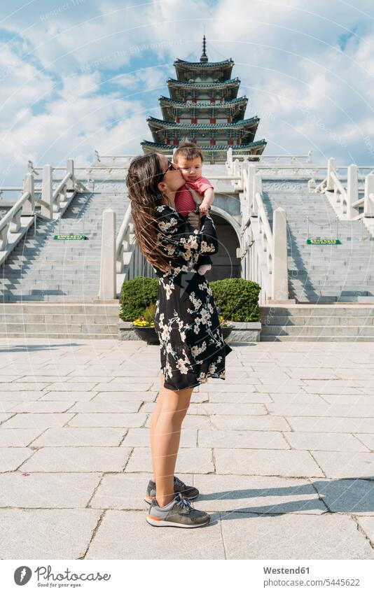 South Korea, Seoul, woman holding and kissing a baby girl in front of the National Folk Museum of Korea, inside Gyeongbokgung Palace journey travelling Journeys