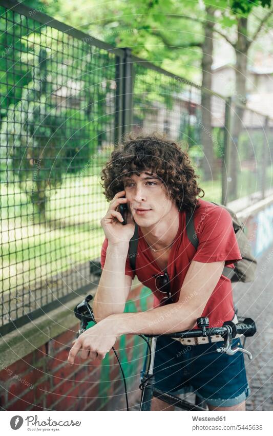 Young man with bicycle on the phone mobile phone mobiles mobile phones Cellphone cell phone cell phones call telephoning On The Telephone calling men males