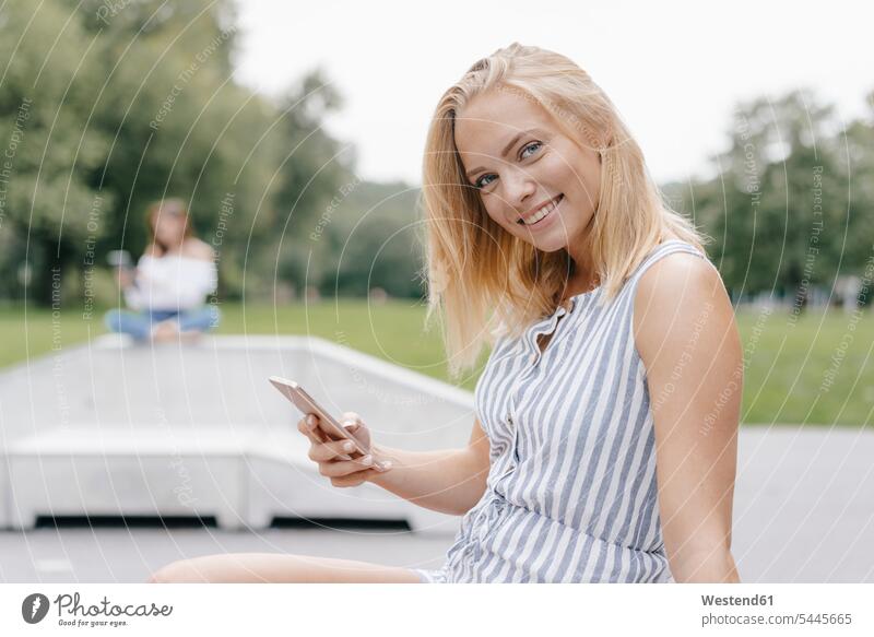 Portrait of smiling young woman with cell phone in a skatepark Skateboard Park skate park portrait portraits smile mobile phone mobiles mobile phones Cellphone