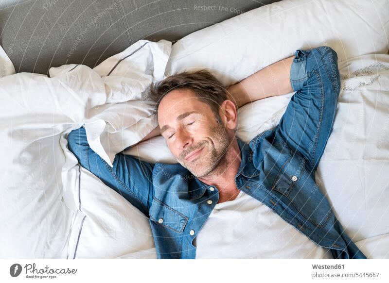 Portrait of mature man lying on bed with eyes closed and hands behind head beds men males portrait portraits Adults grown-ups grownups adult people persons