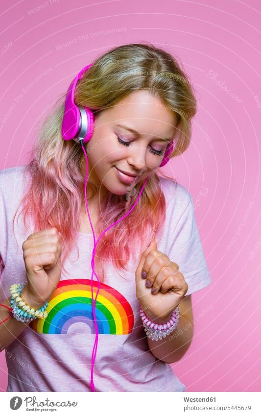 Portrait of dancing young woman listening to music with headphones in front of pink background females women headset portrait portraits Adults grown-ups