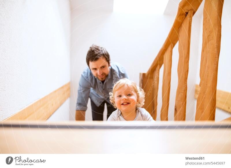Father with little boy on wooden stairs at home baby infants nurselings babies stairway father pa fathers daddy dads papa smiling smile people persons