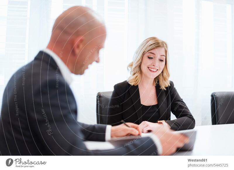 Businessman and businesswoman talking in office offices office room office rooms businesswomen business woman business women smiling smile speaking Business man