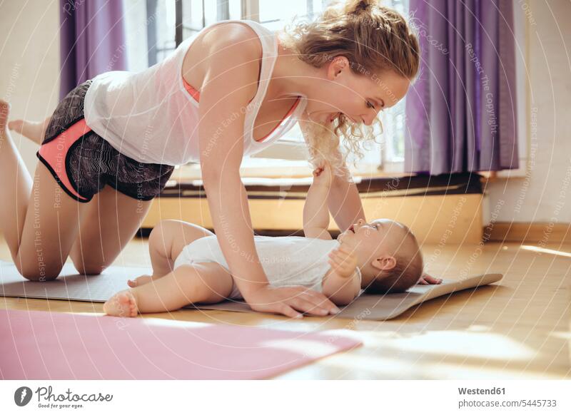 Mother playing with her baby on yoga mat while working out infants nurselings babies exercising exercise training practising mother mommy mothers mummy mama Fun