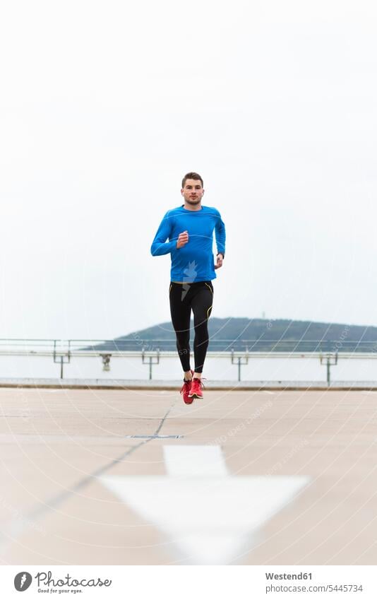 Young man running on parking level Jogging exercising exercise training practising men males fitness sport sports Adults grown-ups grownups adult people persons