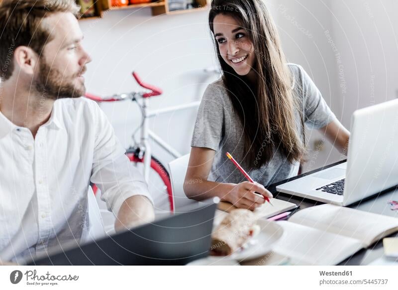 Smiling woman at home using laptop looking at boyfriend Laptop Computers laptops notebook couple twosomes partnership couples smiling smile computer computers