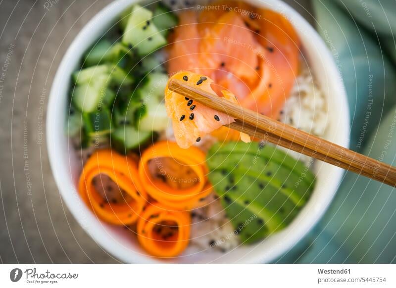 Sushi-Bowl with salmon, cucumber, avocado, rice and carrot, salmon and chopsticks in the foreground overhead view from above top view Overhead Overhead Shot