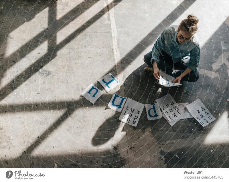 Young woman sitting on concrete floor working on letter templates At Work sunshine Sunny Day sunny females women Adults grown-ups grownups adult people persons