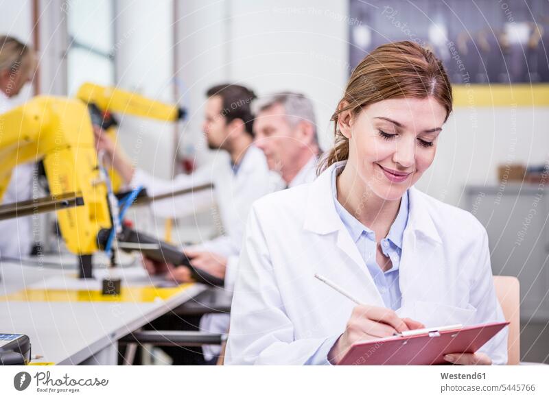 Engineer in factory taking notes on clipboard clipboards clip-board clip-boards clip board factories smiling smile engineer female engineer engineers