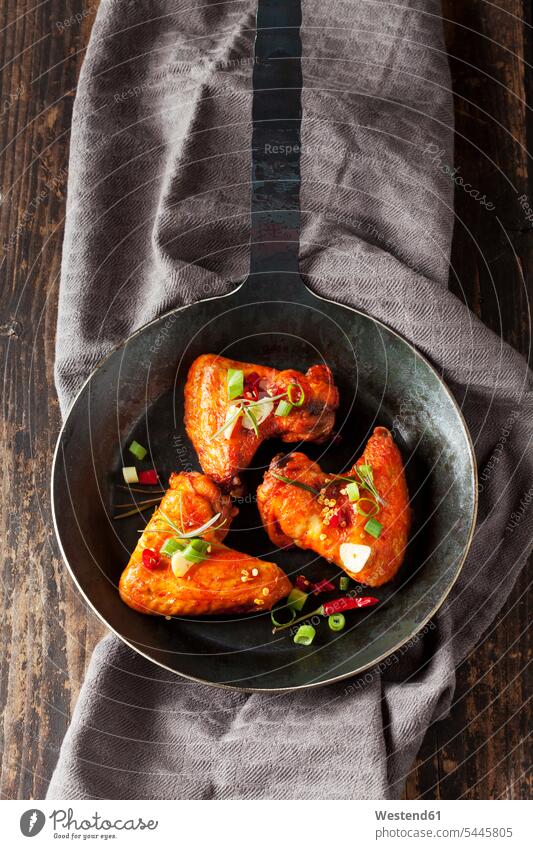 Three marinated and grilled chicken wings in cast-iron frying pan overhead view from above top view Overhead Overhead Shot View From Above Garlic culinary herb