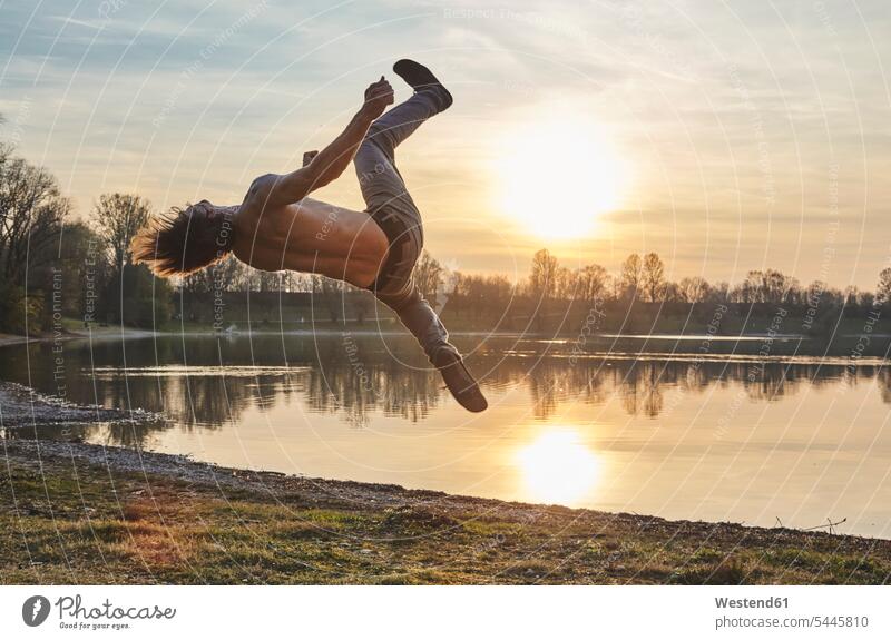 Germany, Bavaria, Feldkirchen, man doing parkour at lakeshore men males Parcour jumping Leaping Adults grown-ups grownups adult people persons human being