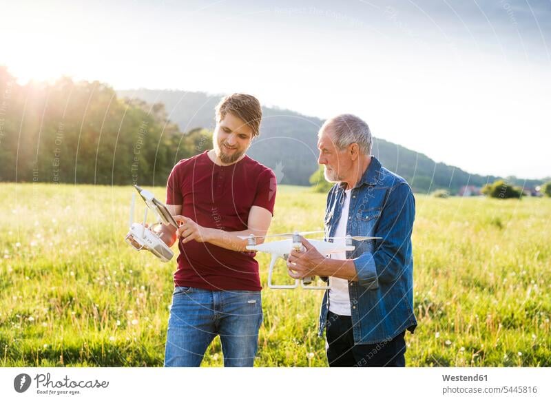 Senior father and his adult son with drone on a field - a Royalty