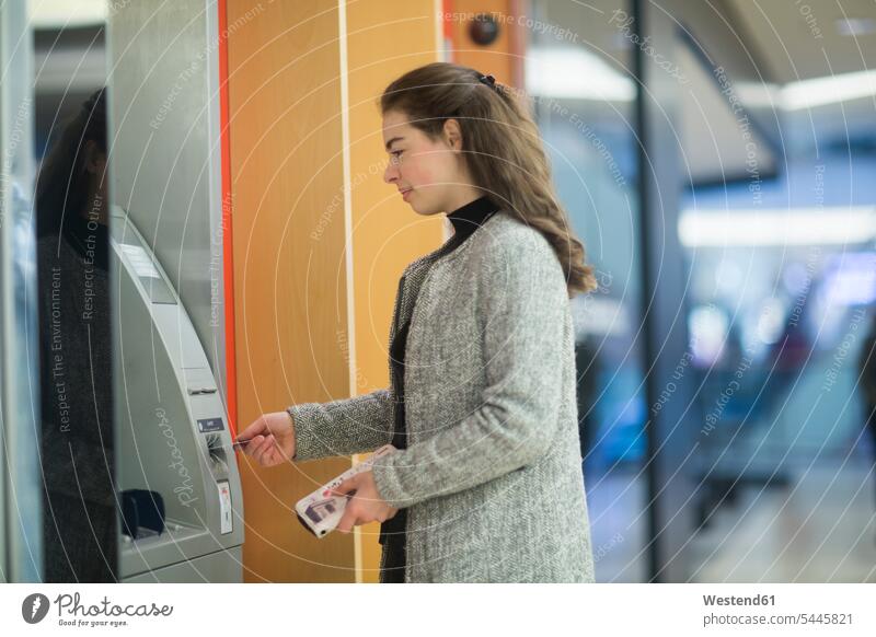 Young woman in a shopping mall using cash machine Shopping Mall females women use Adults grown-ups grownups adult people persons human being humans human beings