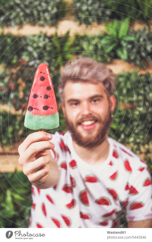 Young man offering watermelon ice lolly, close-up men males hand human hand hands human hands Adults grown-ups grownups adult people persons human being humans