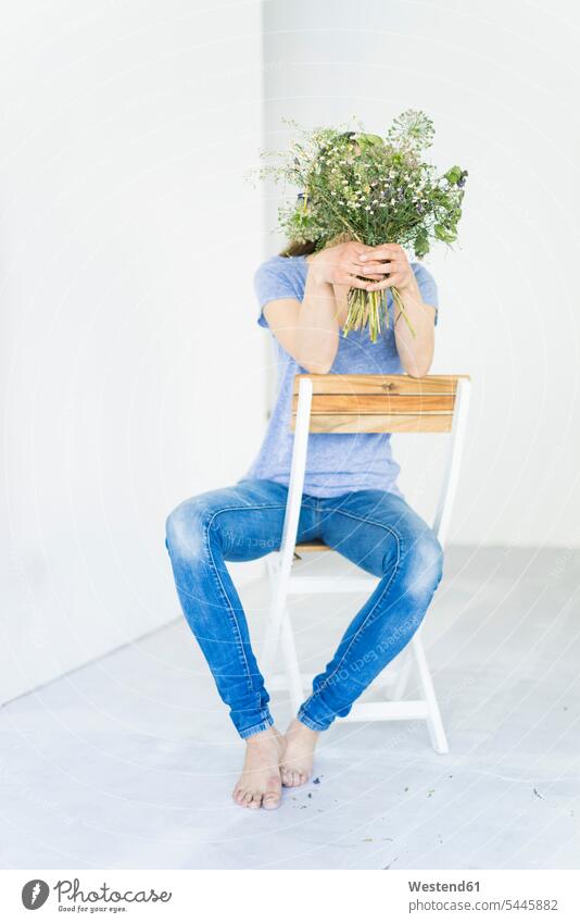 Woman sitting on a chair holding bunch of flowers in front of her face Bunch of Flowers Bouquet Flower Bouquet Bouquet of Flowers Flower Bouquets