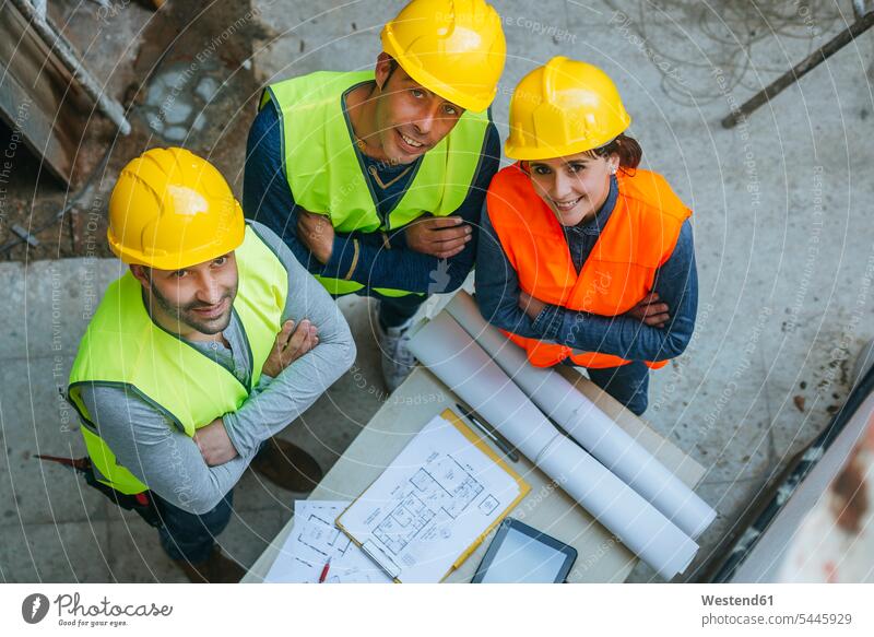 Portrait of smiling woman and two men in workwear with construction plan building plan architectural drawing construction worker builders smile colleagues