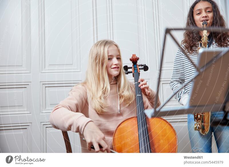 Two girls playing cello and saxophone together females music child children kid kids people persons human being humans human beings Musical Note music sheet