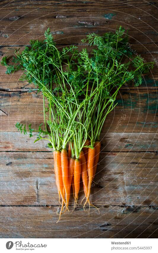Bunch of carrots on wood green Shabby chic bunch bunches firm wooden healthy eating nutrition orange overhead view from above top view Overhead Overhead Shot