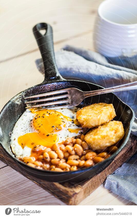Fried egg, baked beans and hash browns in frying pan on wooden board food and drink Nutrition Alimentation Food and Drinks wooden boards wooden panel