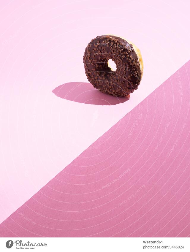 Doughnut with chocolate icing on pink ground food and drink Nutrition Alimentation Food and Drinks magenta Pink background shadow shadows Shades close-up
