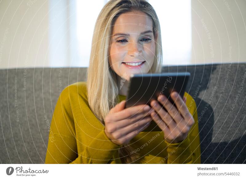 Portrait of smiling woman sitting on couch using mini tablet females women digitizer Tablet Computer Tablet PC Tablet Computers iPad Digital Tablet
