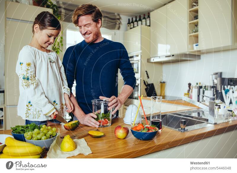 Father and daughter cutting fruit for a smoothie kitchen smiling smile daughters father pa fathers daddy dads papa child children family families people persons