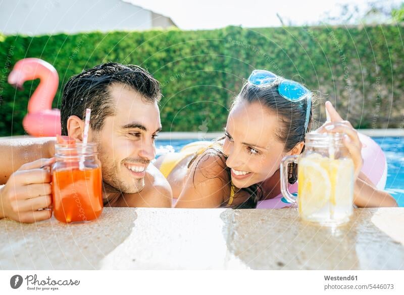 Happy couple in swimming pool with drinks at the poolside relaxed relaxation twosomes partnership couples swimming pools happiness happy smiling smile relaxing