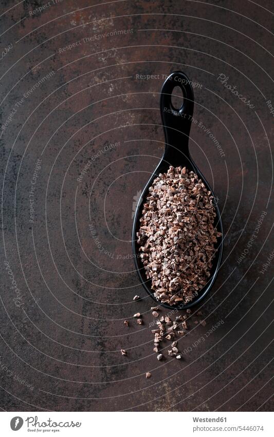 Spoon of crushed raw cacao nibs on rusty metal copy space healthy eating nutrition Fruit Fruits vegan crushing overhead view from above top view Overhead
