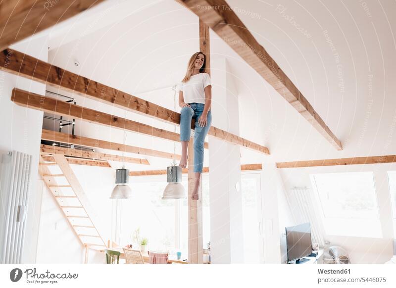 Carefree young woman sitting on ceiling joist Seated smiling smile timber timbers females women ceiling joists Adults grown-ups grownups adult people persons