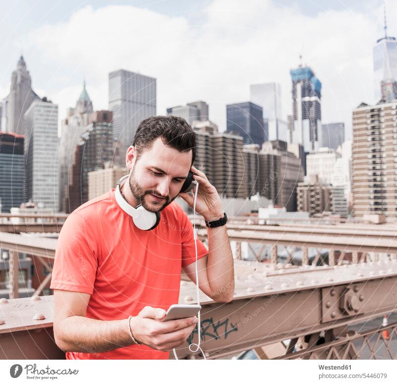 USA, New York City, athlete on Brooklyn Brige with cell phone and headphones headset man men males bridge bridges mobile phone mobiles mobile phones Cellphone