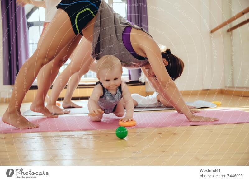 Two mothers working out on yoga mats with babies playing around them Fun having fun funny baby infants nurselings exercising exercise training practising mommy