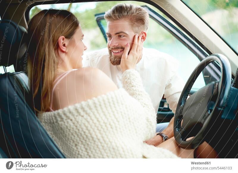 Affectionate young couple in car happiness happy automobile Auto cars motorcars Automobiles Love loving twosomes partnership couples smiling smile looking