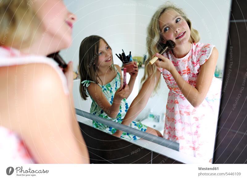 Two girls applying make up in bathroom females applying makeup painting face mirror mirrors smiling smile female friends child children kid kids people persons