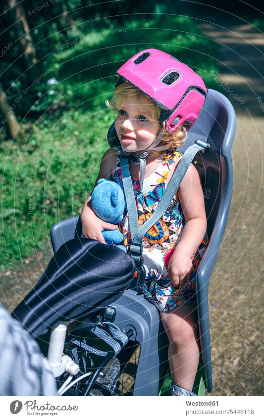 Lttle girl with helmet sitting on a child seat for bicycle helmets Protective Headwear Child's Seat child safety seat females girls Seated bikes bicycles