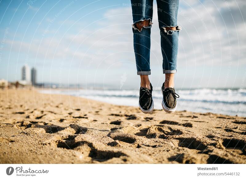 Spain, Barcelona, legs of young man jumping in the air on the beach human leg human legs beaches Leaping people persons human being humans human beings jumps