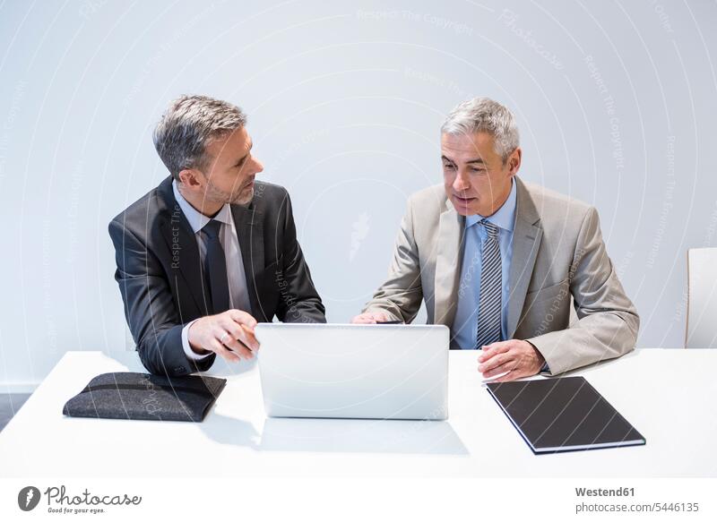 Two businessmen working together in office laptop Laptop Computers laptops notebook At Work sitting Seated offices office room office rooms discussing