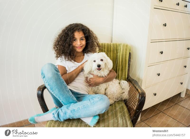Animal loving little girl sitting in armchair petting her white dog dogs Canine stroking animal-loving fond of animals love of animals females girls playing