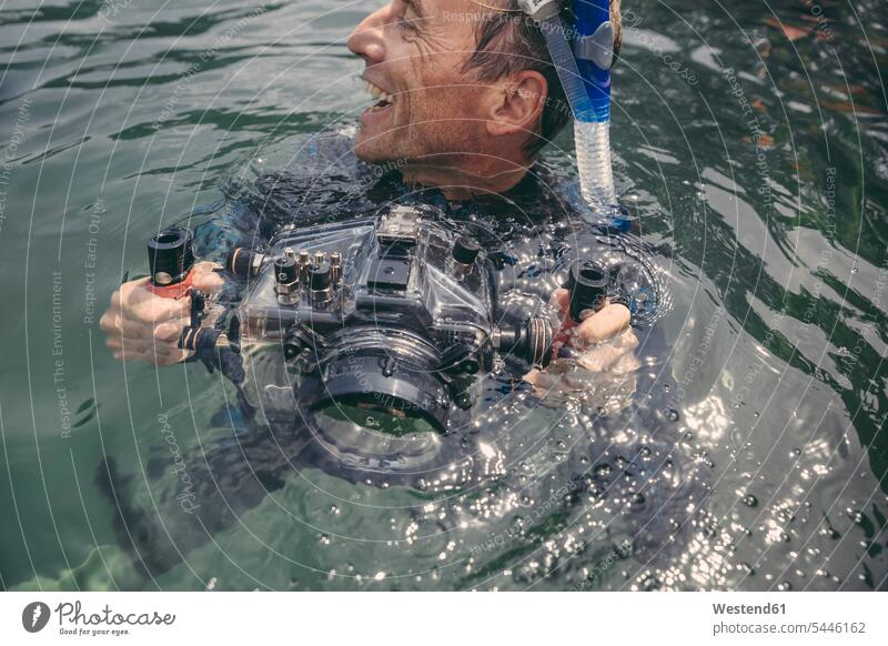 Happy man with underwater DSLR camera case in a lake cameras men males diving dive diver divers laughing Laughter Adults grown-ups grownups adult people persons
