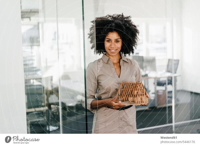Portrait of smiling young woman in office holding architectural model females women portrait portraits standing businesswoman businesswomen business woman