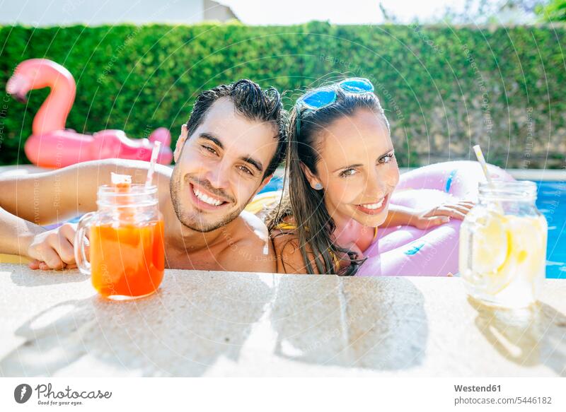 Happy couple in swimming pool with drinks at the poolside relaxed relaxation twosomes partnership couples swimming pools happiness happy smiling smile relaxing