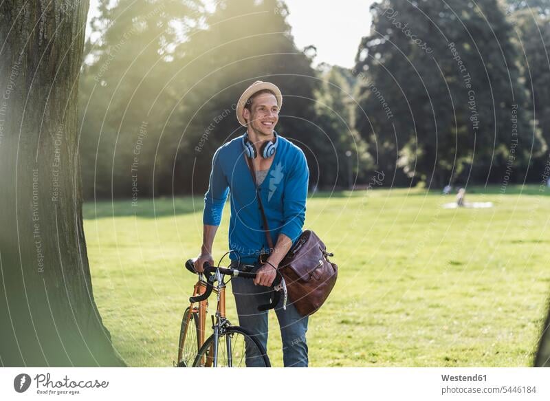 Portrait of relaxed man with racing cycle in a park men males parks Adults grown-ups grownups adult people persons human being humans human beings hat hats