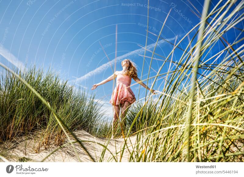 Netherlands, Zandvoort, happy woman standing in dunes with outstretched arms females women sand dune sand dunes beach beaches Adults grown-ups grownups adult