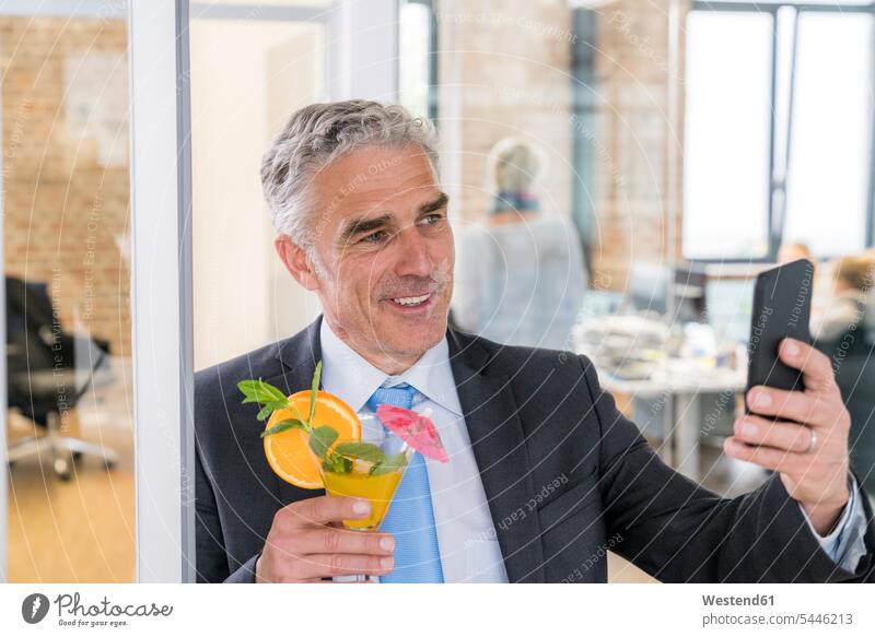 Mature businessman drinking cocktail while taking a selfie Cocktail Cocktails Long Drinks on the phone call telephoning On The Telephone calling celebrating