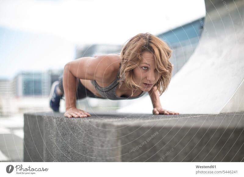 Young woman doing push-ups in the city exercising exercise training practising athlete sportswoman athletes female athlete sportswomen female athletes pushup