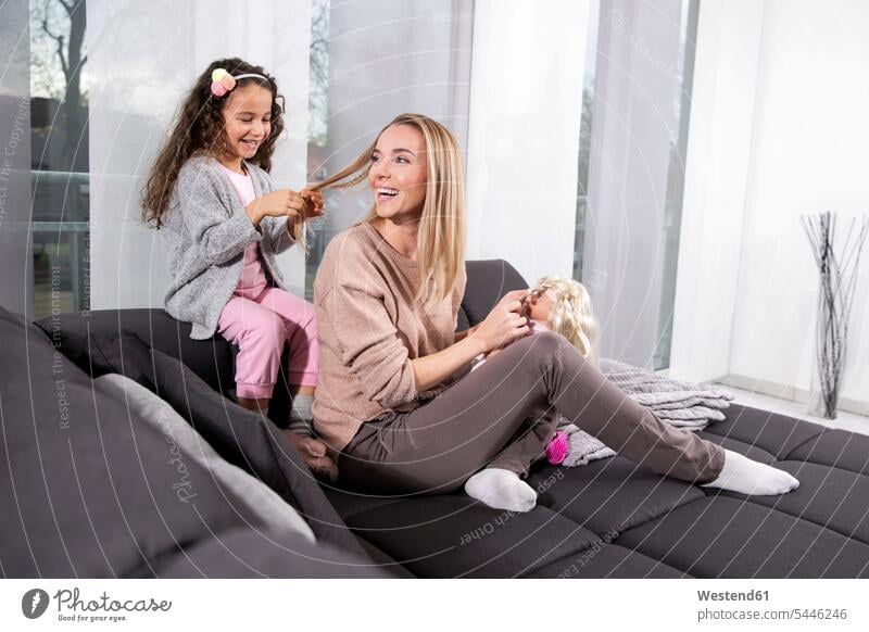 Little girl braiding her mother's hair on the couch mommy mothers ma mummy mama females girls settee sofa sofas couches settees Plaiting parents family families