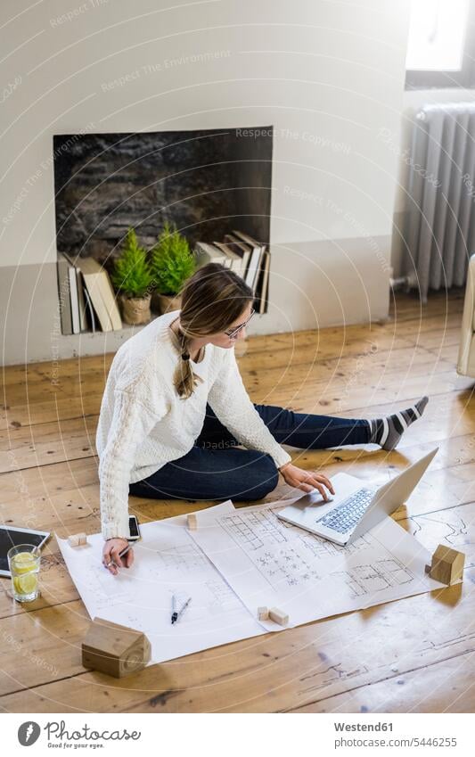 Woman sitting on the floor with blueprint and laptop floors Laptop Computers laptops notebook Seated woman females women Blueprint Blueprints Building Plan