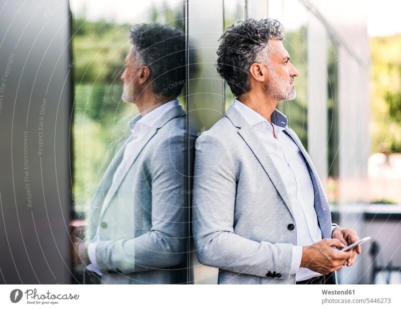 Mature businessman with cell phone at the window windows Businessman Business man Businessmen Business men mobile phone mobiles mobile phones Cellphone