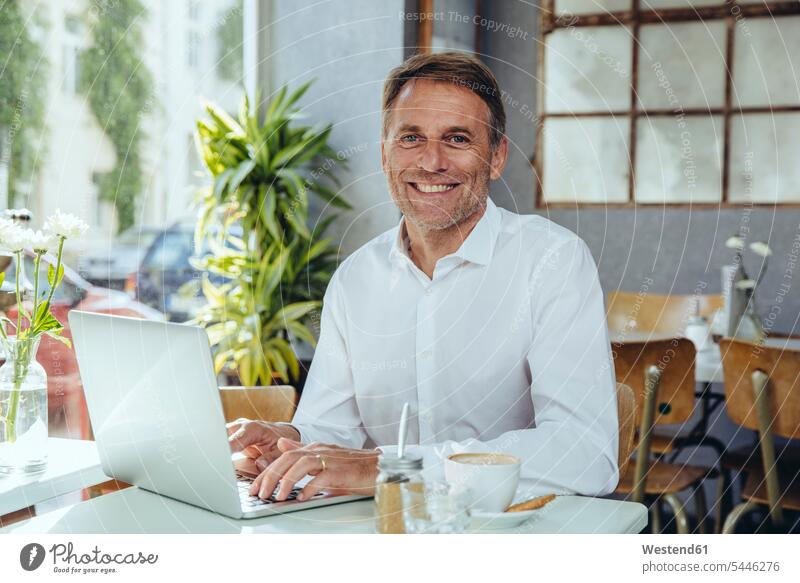 Portrait of smiling businessman working in cafe with laptop Laptop Computers laptops notebook Businessman Business man Businessmen Business men smile At Work