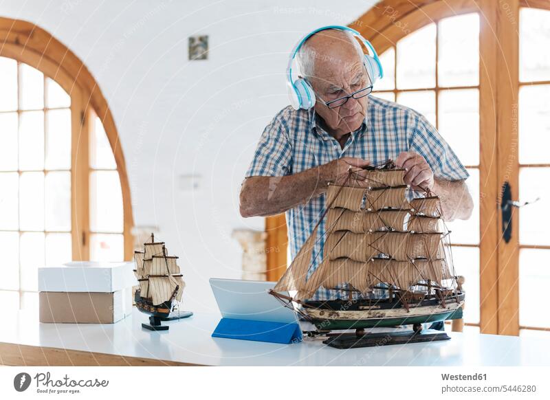 Senior man wearing headphones working on model ship on table with tablet digitizer Tablet Computer Tablet PC Tablet Computers iPad Digital Tablet